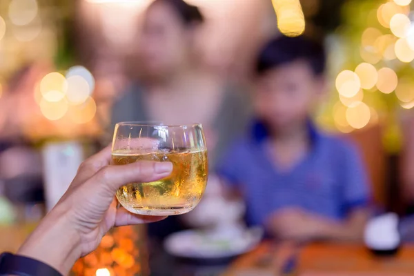 Woman hand holding glass of whiskey at family dinner party. — Stock Photo, Image