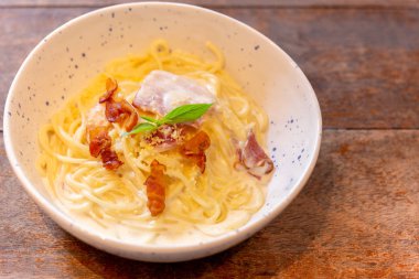 Ahşap masada pastırma ve jambon ile Spagetti carbonara.