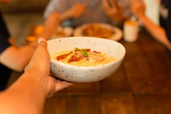 Tjener serverer spaghetti carbonara på tallerkenen i restauranten . - Stock-foto