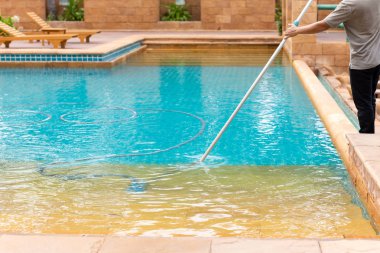 İşçi sabahları vakum tüpü ile yüzme havuzu Temizleme.