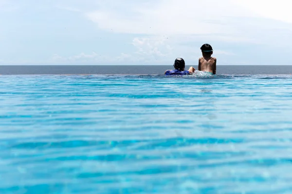 Anne ve genç oğlu yüzme havuzunda yaz tatilinde okyanusa bakarak rahatlayın. — Stok fotoğraf