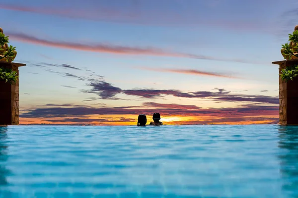 Mãe e filho relaxam na piscina assistindo ao pôr do sol sobre o oceano nas férias de verão . — Fotografia de Stock