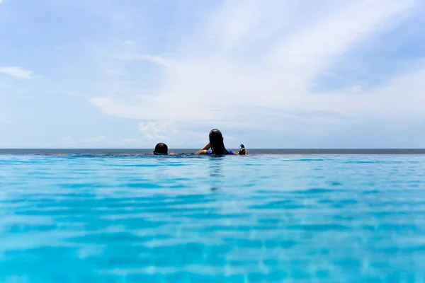 Matka i młody syn relaks w basenie patrząc nad oceanem na wakacjach. — Zdjęcie stockowe