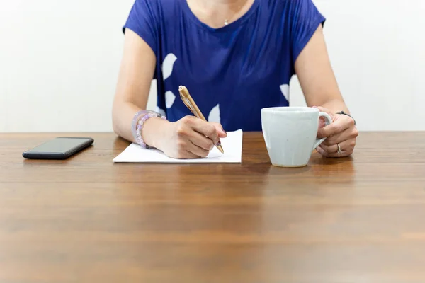 女商人在办公桌上用一杯咖啡手写文书工作. — 图库照片