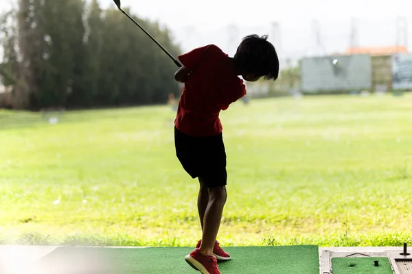 Jovem asiático menino está praticando seu balanço de golfe no campo de golfe . — Fotografia de Stock