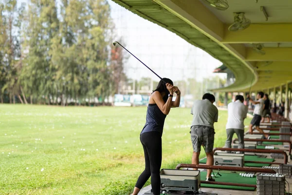 Mulher asiática praticando seu balanço de golfe na gama de condução de golfe . — Fotografia de Stock