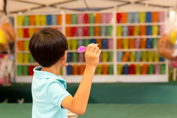 Мальчик играет в дартс с разноцветными воздушными шарами на ярмарке . — стоковое фото