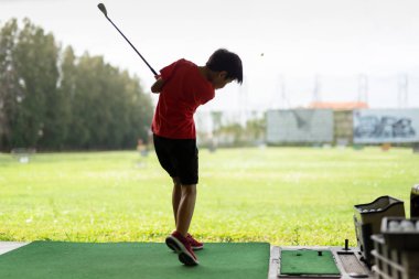 Genç asyalı çocuk golf sürüş aralığında onun golf salıncak pratik.