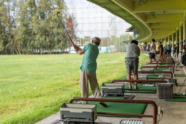 Senior man exercise practicing his golf swing at golf driving range. — Stock Photo, Image