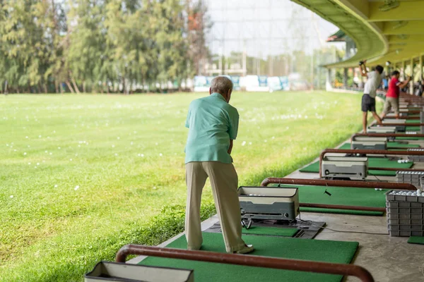 Exercício de homem sênior praticando seu balanço de golfe na gama de condução de golfe . — Fotografia de Stock