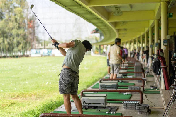 Člověk trénuje golfový švih na golfovém dostřel. — Stock fotografie