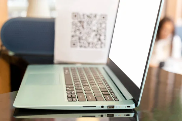 Business computer laptop on counter table with blur QR code in blur background.