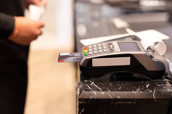 Cajero que utiliza la máquina de la tarjeta de crédito para el pago de compras del cliente en tienda . — Foto de Stock