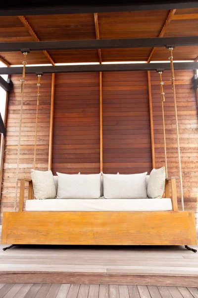 Εξωτερική βεράντα μεγάλη κούνια ξύλινη καρέκλα με μαξιλάρι στη βεράντα με ξύλινο δάπεδο. — Φωτογραφία Αρχείου