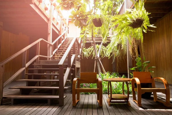 Wooden stair with arm chair and plant in terrace.