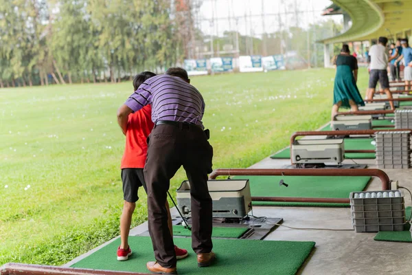 Treinador pessoal dando aula para o jovem menino na condução de golfe tocou — Fotografia de Stock