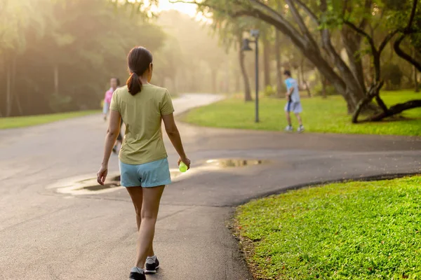 Ejercicio de mujer caminando en el parque con agua de botella al amanecer . — Foto de Stock