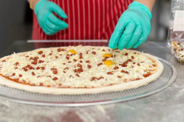 Şefler mutfak masasında bıldırcın yumurtası ile pizza hazırlıyorlar.,