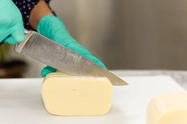 Bıçaklı eller beyaz tahtada peynir kesiyor..