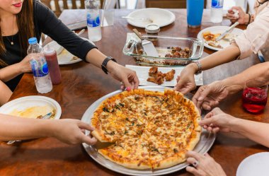 Üst düzey aile üyeleri, öğle yemeği için masaya uzanmış pizzacıya uzanıyorlar..