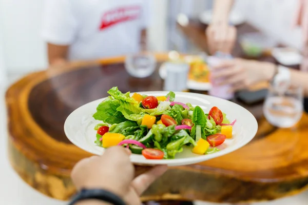 Serveur servant une salade de légumes frais au restaurant . — Photo