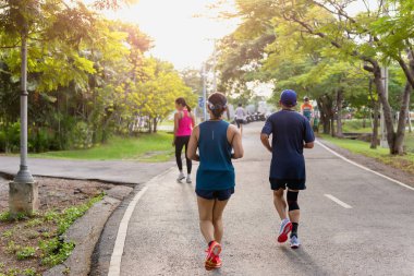 İnsanlar sabah güneş doğarken parkta koşuyorlar..