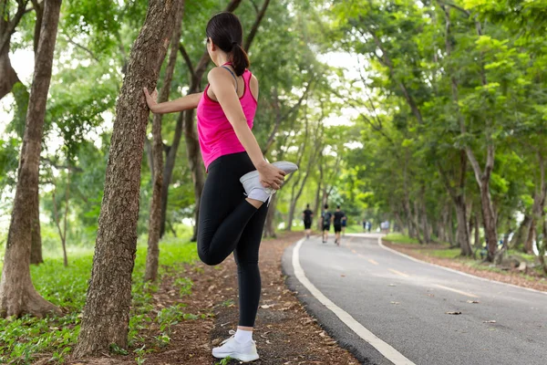 Mujer estirando aquí músculo de la pierna prepararse para el ejercicio en el parque . — Foto de Stock