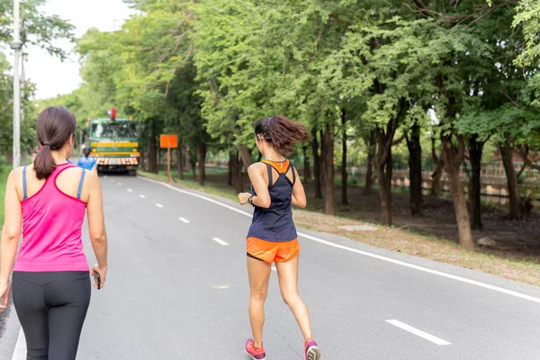 Mujeres corriendo en pista en el parque mientras escuchan música en el teléfono móvil . — Foto de Stock