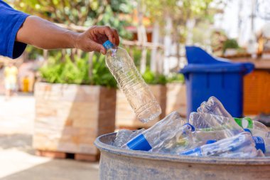 Temizlik için çöp kutusunda geri dönüşümlü plastik şişeyi tutan el..