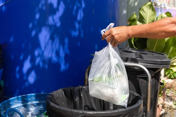 Mano mettendo sacchetti di plastica rifiuti nel cestino della spazzatura . — Foto Stock