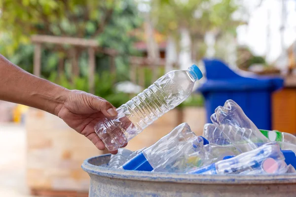 Tenuta in mano bottiglia di plastica riciclabile nel cestino della spazzatura per la pulizia . — Foto Stock