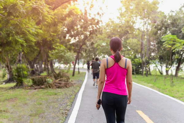 Ejercicio de mujer caminando en el parque con la mano sosteniendo el teléfono celular . — Foto de Stock