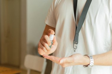 Ofiste çalışan yeni normal bir adam mikropları temizlemek için eline alkol sıkar.