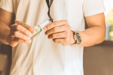 Yeni normal erkek eli boyun kayışı için yapılmış şişe dezenfektanı spreyini gösteriyor.