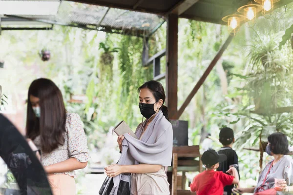 New normal women in protective face mask queuing at cafe counter