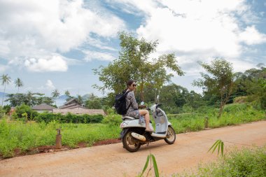 Güzel bir okyanus manzarası olan motosikletli bir turist kadın.