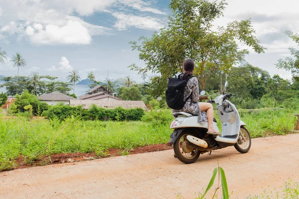 Güzel bir okyanus manzarası olan motosikletli bir turist kadın.
