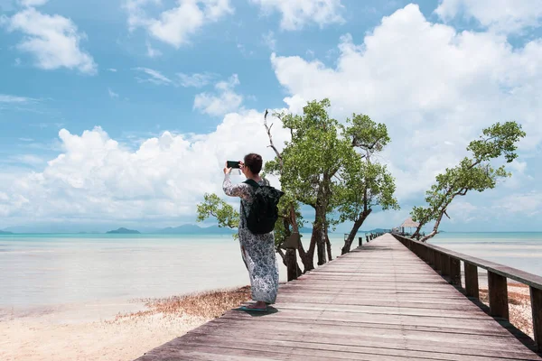 Turystka Korzystająca Telefonu Komórkowego Robi Zdjęcie Oceanu Drewnianym Moście — Zdjęcie stockowe