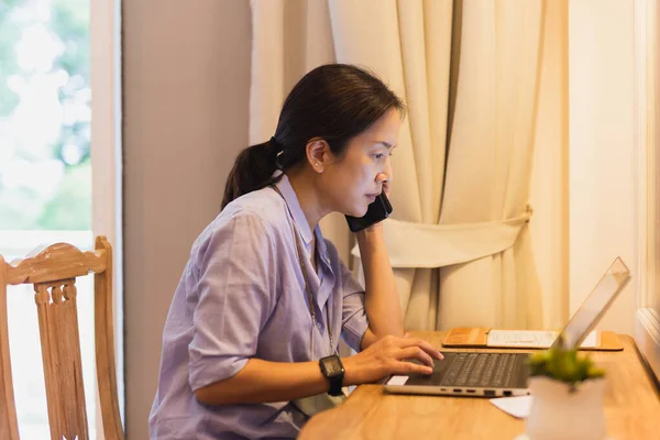 在笔记本电脑上工作时打电话的女商人 — 图库照片