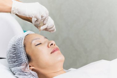 Asyalı bir kadının güzel portresi, temiz yüzlü bir pipet yağıyla spa tedavisi görüyor.