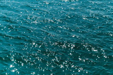 Güneş ışığından gelen bokeh ile arka plandaki okyanus dalgaları su yüzeyine yansıyor