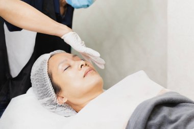 Profesyonel kozmetikçi yağ pipeti kullanıyor. Müşterilerin yüzüne serum uygula.