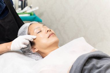 Profesyonel kozmetikçi yağ pipeti kullanıyor. Müşterilerin yüzüne serum uygula.