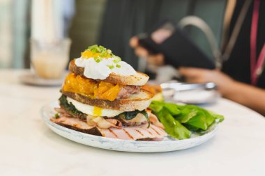 Pastırma, jambon ve yumurta, kahvaltı için tabakta sandviç.