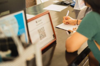 İş kadını resepsiyonda otel sözleşmesi imzalıyor.