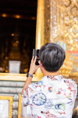 Budist rahiplerin cep telefonuyla ilahi söylerken fotoğraflarını çeken bir turist.