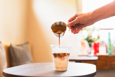 Kahveci espresso dolduruyor, kafede buzlu latte yapıyor.