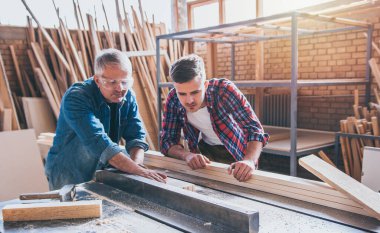 Marangozlar atölyede testere kullanıyorlar.