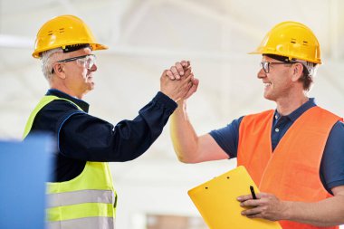 Bir mühendis ve bir yönetici koruyucu giysi, tokalaşma ve başarı giyerek bir fabrikada birlikte çalışıyorlar. 