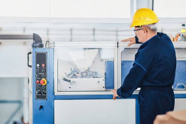 Mavi takım elbiseli, sarı kasklı bir fabrika işçisinin portresi. 